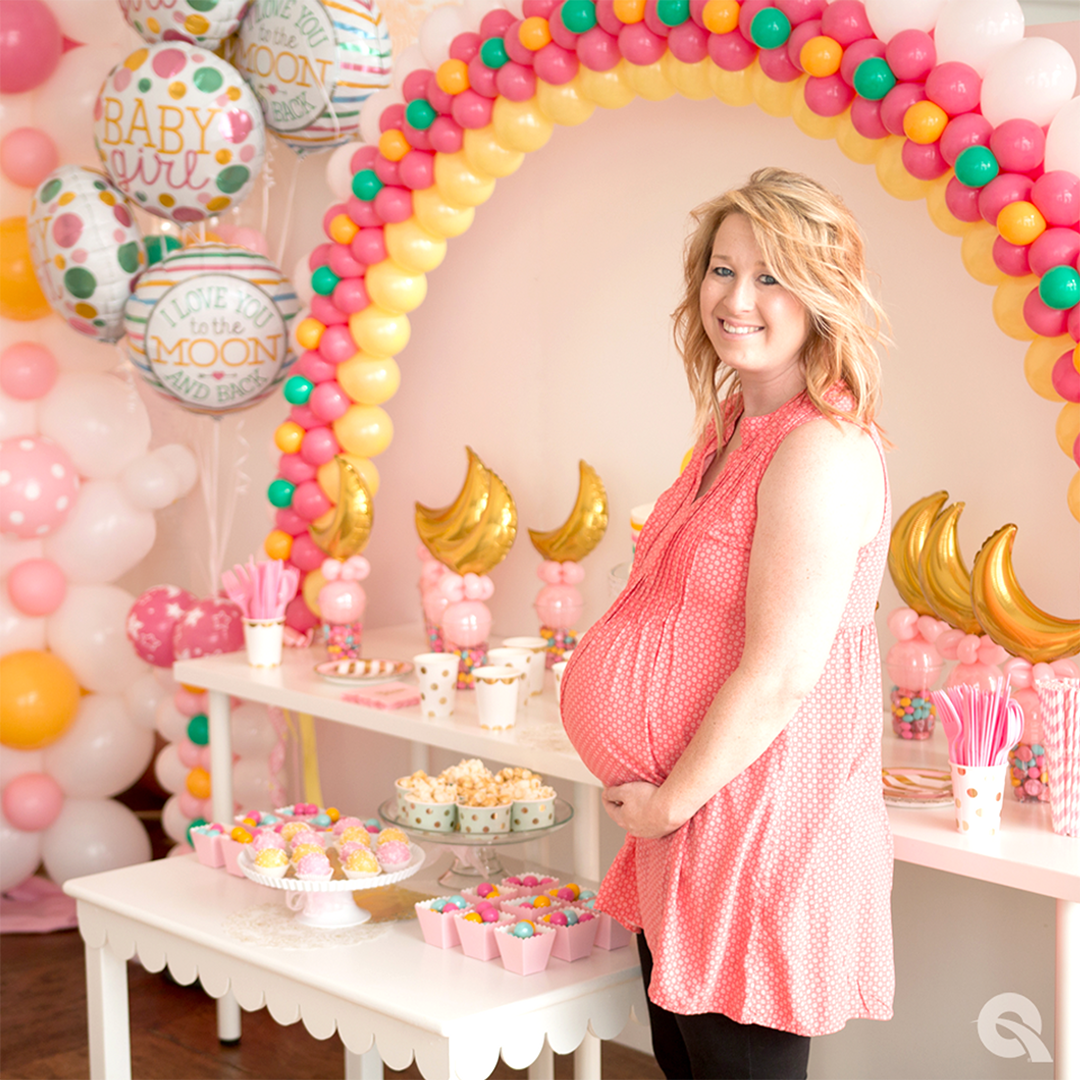 pregnant women standing in front of baby shower balloon display