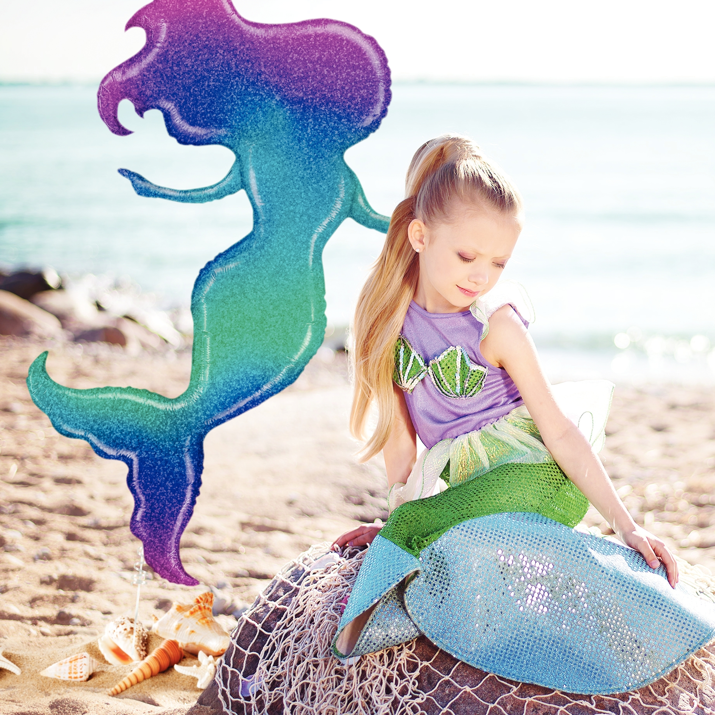 little girl in mermaid costume on beach with mermaid balloon